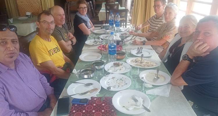 Group of trekkers sharing a casual meal around a long table in a modest restaurant.