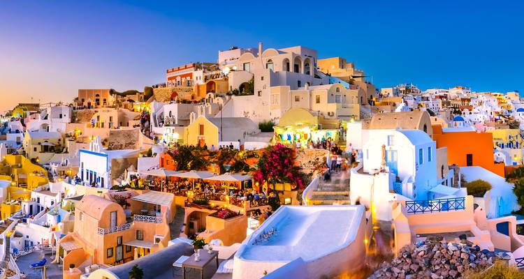 Evening glow over a lively quarter of Santorini with colorful houses and terraces lit against the cobalt sky.