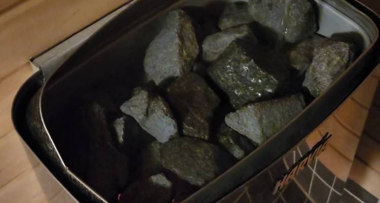 Close-up of hot sauna stones heating inside a metal stove.