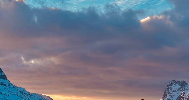 Snow-draped peaks beneath a colourful sunrise sky with pink and blue clouds.