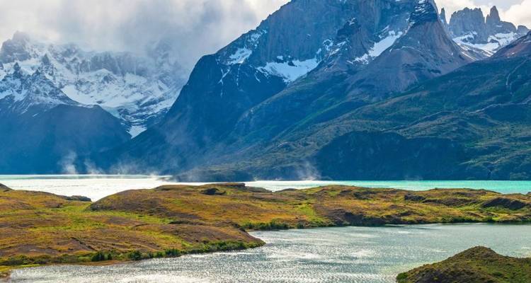 Las aguas color turquesa humeante se encuentran con la península verde ondulante y las montañas escarpadas y dramáticas que se alzan detrás.