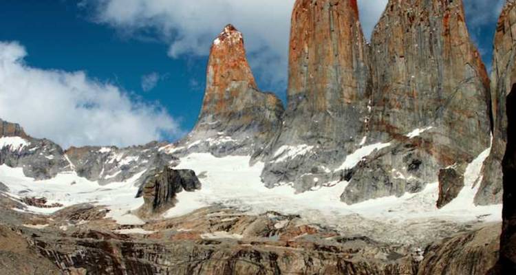 Las icónicas torres de granito se alzan sobre campos de nieve y morrena glacial bajo un cielo azul profundo.