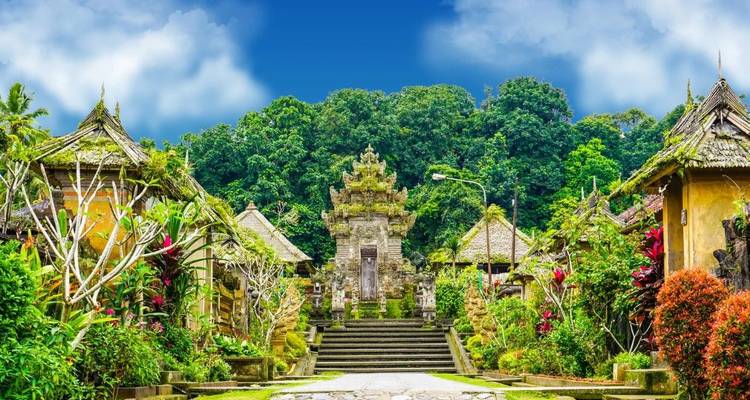 Traditional Balinese temple courtyard framed by lush tropical greenery and bright sky