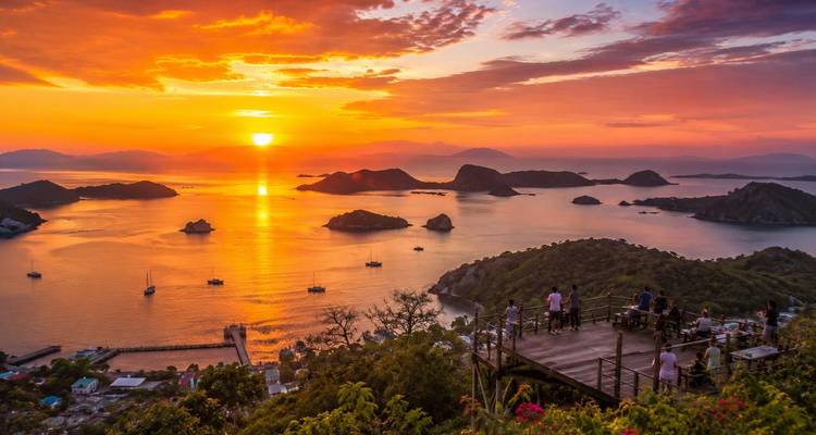 Glorious sunset over an archipelago viewed from a hilltop deck with visitors and boats below