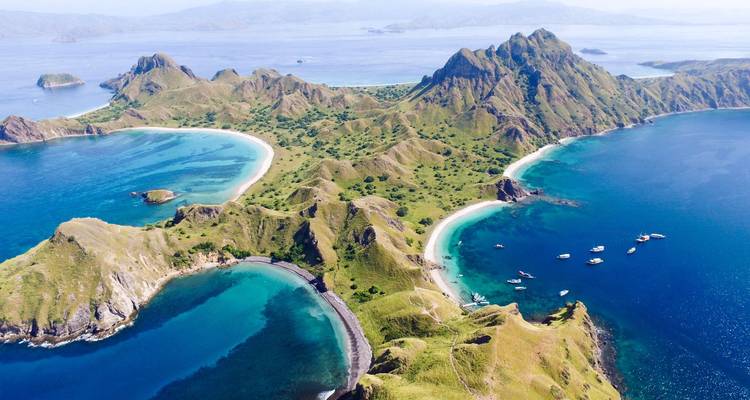 Stunning aerial of green ridged island with multiple blue coves and anchored boats