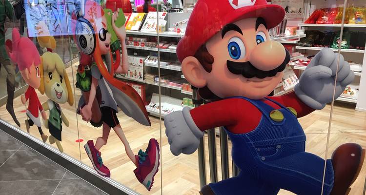 Storefront window featuring life-size Super Mario and Nintendo characters inside retail shop.