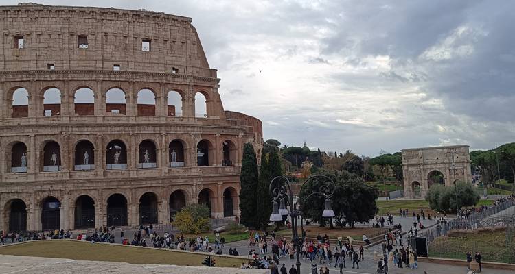Expansive scene of the Colosseum and Arch of Constantine with crowds exploring the grounds