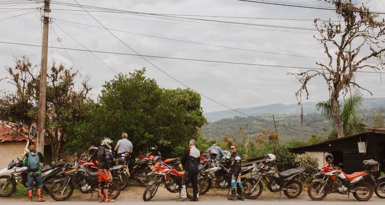 Große Gruppe von Motorradfahrern und Motorrädern, die sich neben einer Landstraße versammelt haben.
