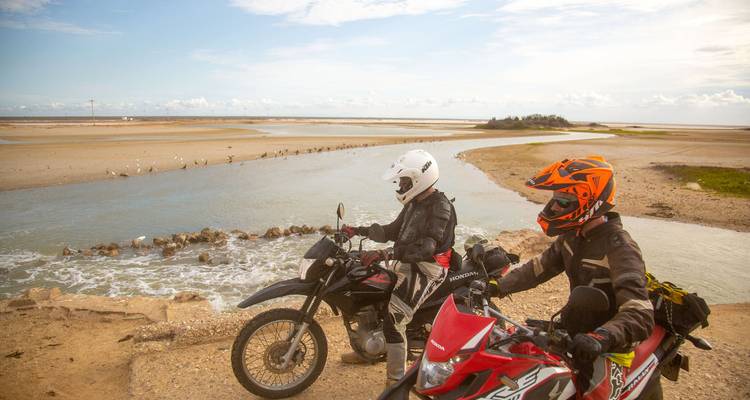 Dos ciclistas se detienen para admirar los canales de marea y bancos de arena a lo largo de una costa remota.