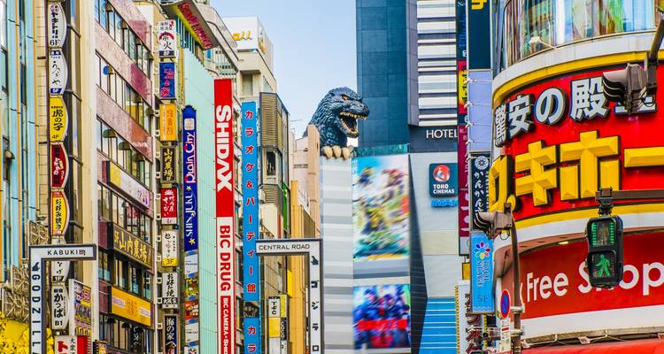 Colorful skyscraper canyon of Shinjuku’s Godzilla Road with neon signs and Godzilla head peering out.