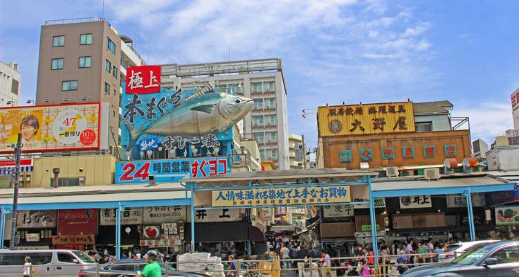 Tsukiji outer market frontage with oversized tuna model and bustling shoppers on a sunny day.