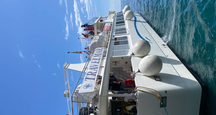 Witte Travelmar veerboot met passagiers aan boord die vaart op zee met helder blauw water onder een heldere hemel