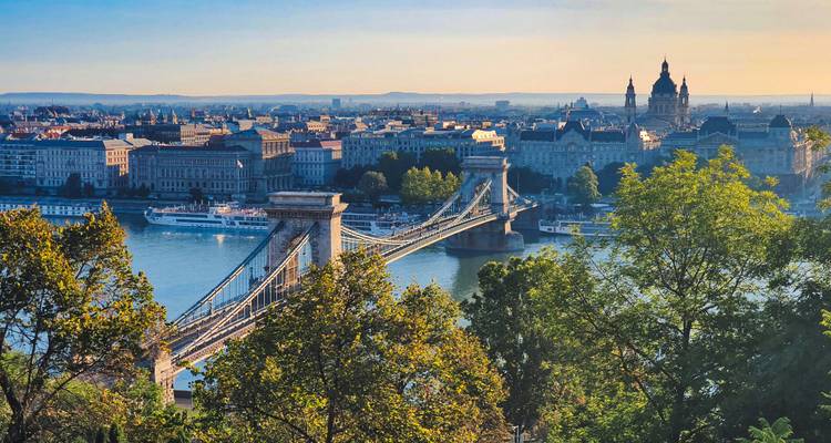 Panoramic view of Budapest with the Chain Bridge spanning the Danube River framed by leafy trees