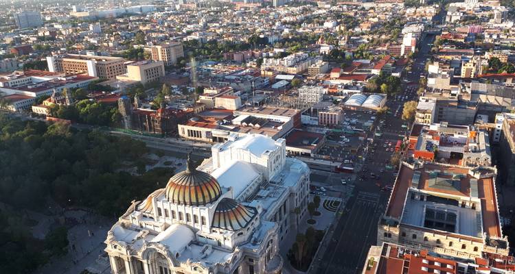Golden sunset light over Mexico City with the Palacio de Bellas Artes and bustling avenues seen from above.