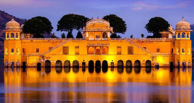 El palacio Jal Mahal se ilumina sobre las aguas tranquilas del lago Man Sagar al atardecer.