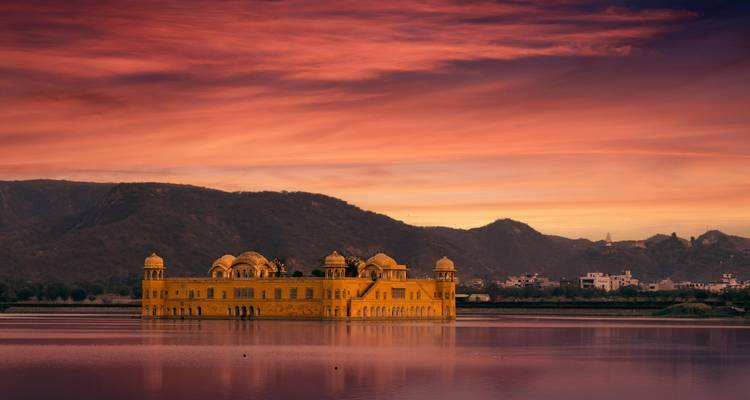 Jal Mahal se refleja en aguas tranquilas bajo un cielo al atardecer de un púrpura-rosa vivido.