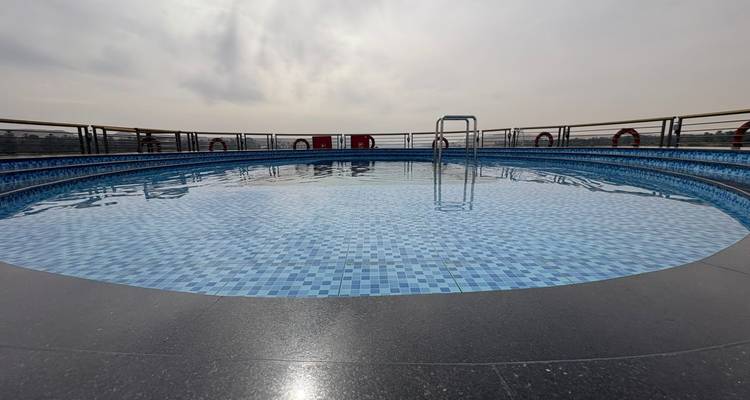Primer plano de una piscina redonda vacía en la cubierta superior de un crucero bajo un cielo brumoso.