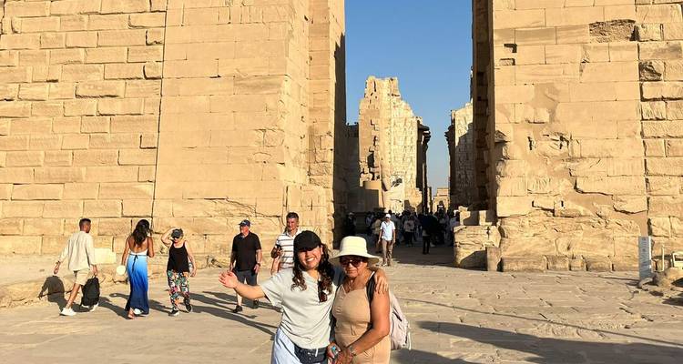 Visitantes explorando una majestuosa puerta de arenisca antigua en el Templo de Karnak, dos mujeres posando felices en primer plano.