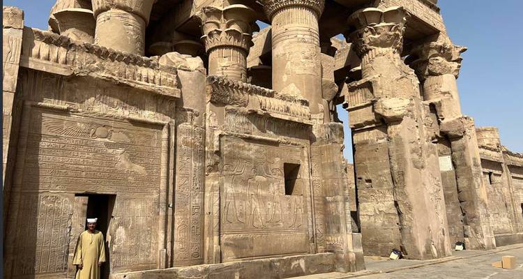 Columnas de piedra y relieves del Templo de Kom Ombo con un guardia vestido de forma tradicional en la puerta.