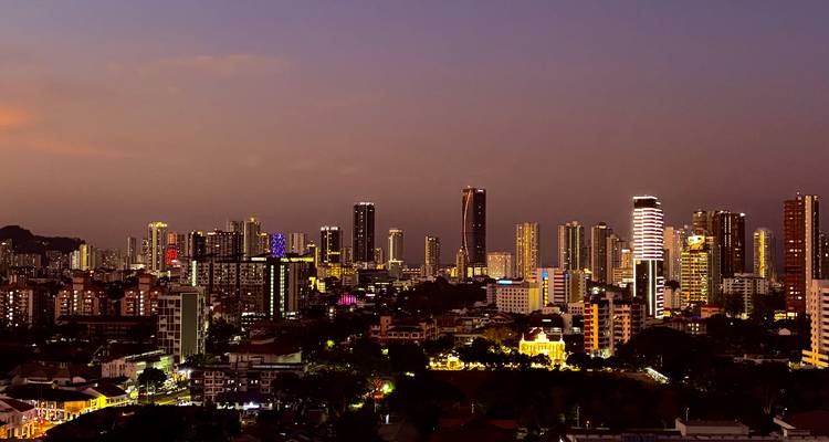 Skyline de la ville de Penang au crépuscule avec d'innombrables lumières d'appartements scintillant sous un ciel pourpre.