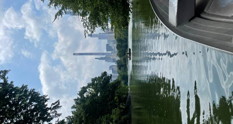 Lac calme de Central Park avec des barques à rames et les gratte-ciel de Midtown encadrés par des arbres verdoyants.
