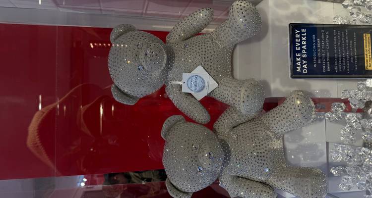 Exposition de deux oursons en peluche recouverts de cristaux avec signalétique promotionnelle.