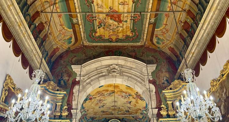 Richly decorated church interior with painted baroque ceiling, gilded altars and sparkling crystal chandeliers.
