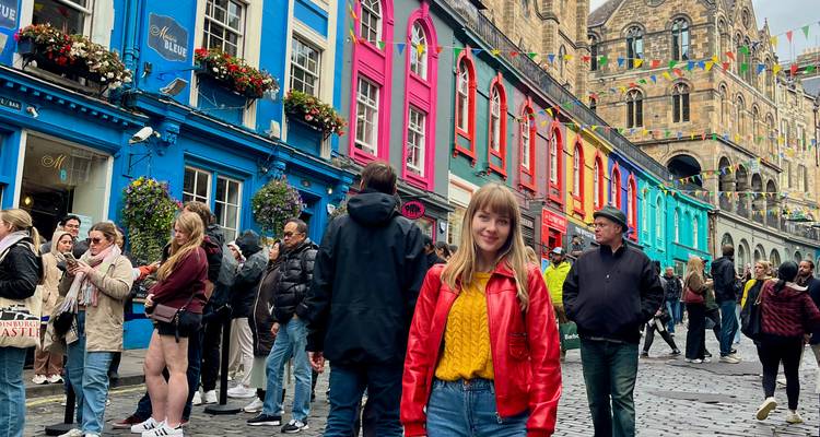 La rue Victoria animée, bordée de boutiques aux couleurs vives et décorée de guirlandes festives, avec une femme souriante vêtue d'une veste rouge au centre.