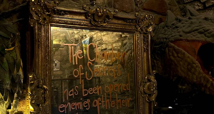 Miroir doré orné avec une écriture orange indiquant « The Chamber of Secrets has been opened » dans une lumière tamisée.
