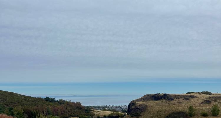 Vue panoramique dégagée sur le Firth of Forth avec des pentes herbeuses au premier plan.