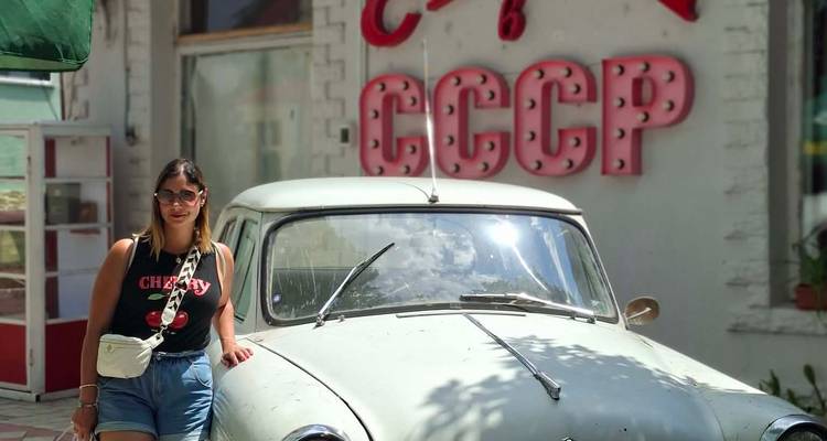 Jeune femme posant à côté d'une voiture soviétique d'époque vintage devant un panneau rétro CCCP.