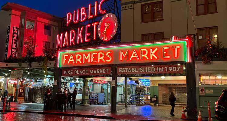 Le centre du marché public éclairé au néon avec l'enseigne du marché fermier qui brille lors d'une nuit humide.