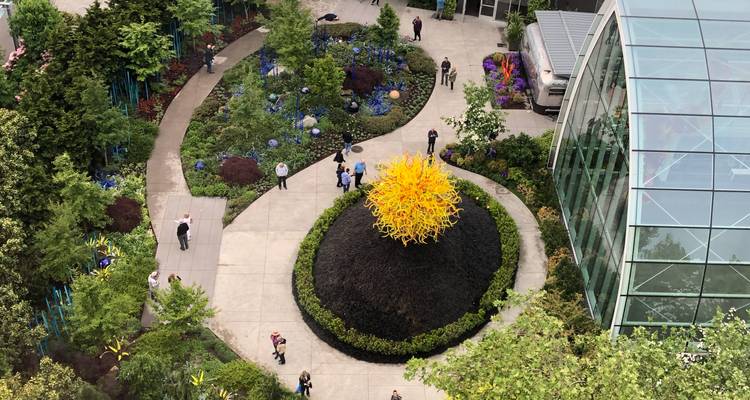 Vue aérienne du jardin Chihuly avec une sculpture en verre jaune vif et des sentiers sinueux.