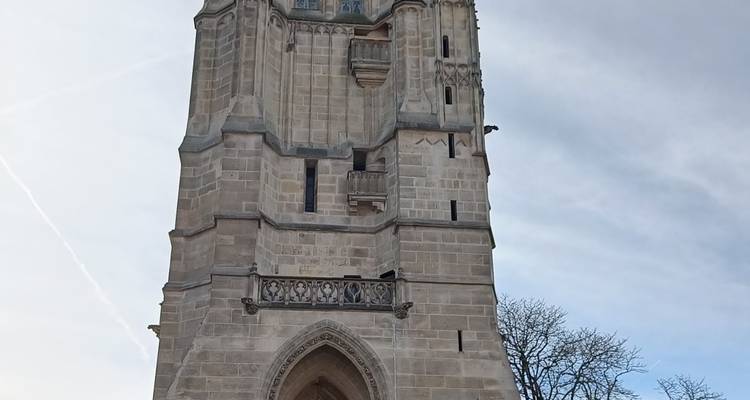 Gothic stone Tour Saint-Jacques tower reaching into a lightly clouded sky.