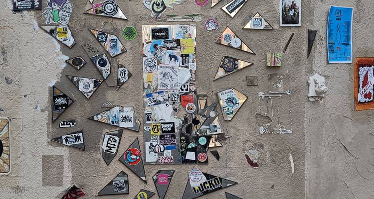 Urban wall covered with colorful stickers and small pieces of street art forming a collage.