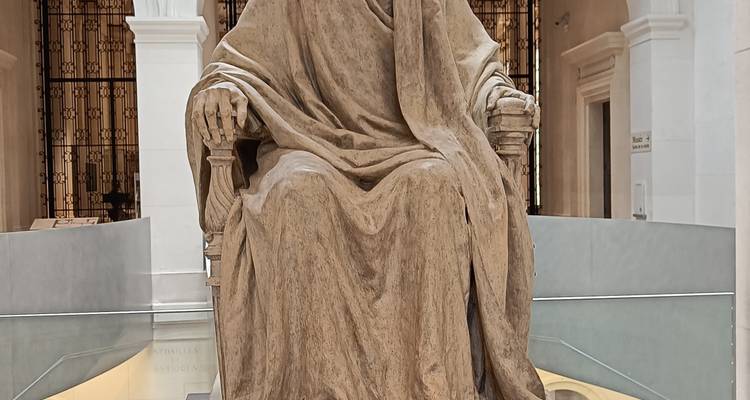 Large seated stone statue displayed prominently in a bright museum hall.