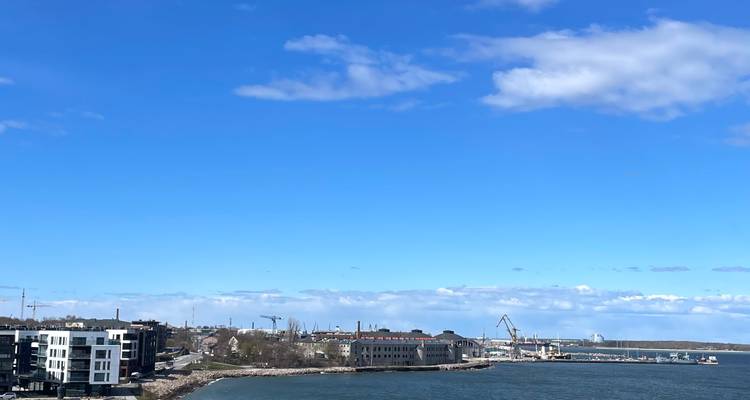 Ligne côtière du port avec des appartements modernes, des grues et un ciel bleu lumineux à Tallinn