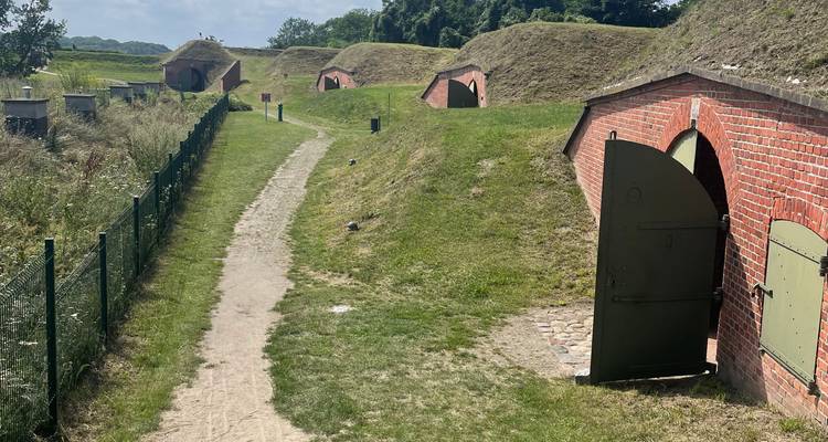 Des blockhaus couverts de gazon reliés par un sentier de terre à un ancien fort côtier.