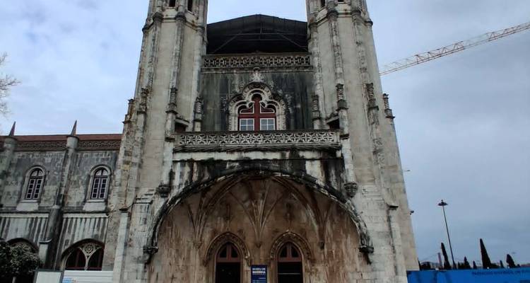 Weathered Gothic church façade under renovation with crane and cloudy sky.