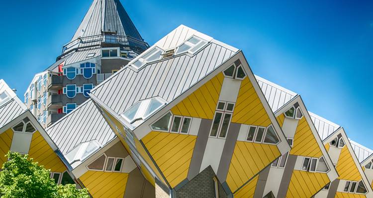 Iconic tilted yellow Cube Houses stand sharply against a deep blue sky.