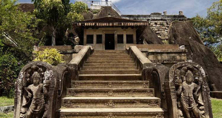 Ancient stone stairway flanked by guardian carvings leading to a hilltop shrine.