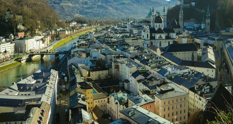 Vue panoramique sur la ligne d'horizon baroque de Salzbourg, le fleuve et les collines environnantes depuis un point de vue élevé.