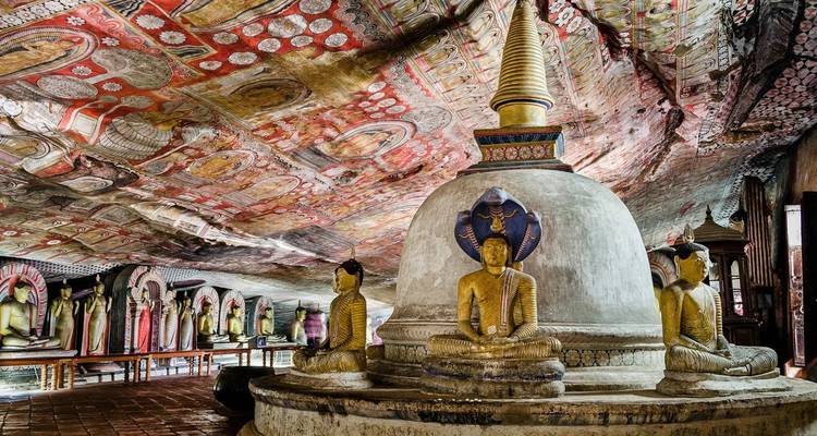 Intérieur orné du Temple de la Grotte de Dambulla avec des fresques colorées, une stupa centrale et des images de Bouddha.