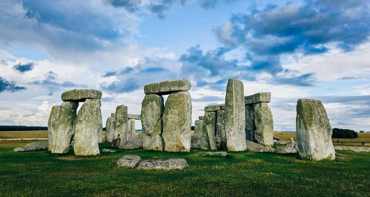 Cercle de pierres préhistorique emblématique de Stonehenge se dressant sur une plaine herbeuse ouverte sous des nuages dramatiques.