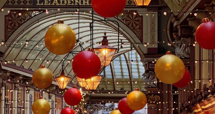 Intérieur d'une élégante halle de marché victorienne ornée de boules rouges et dorées suspendues et de guirlandes lumineuses.