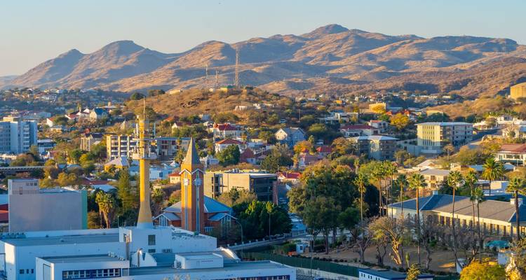 Panoramisch uitzicht op de skyline van Windhoek met de Christuskirche en omringende heuvels bij zonsondergang.
