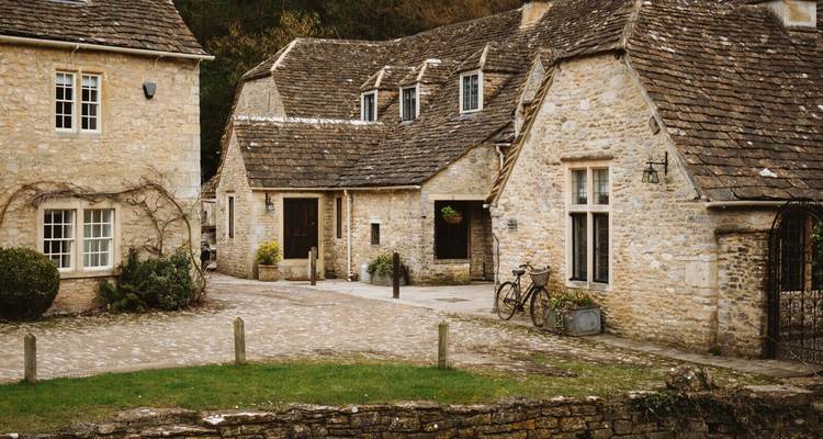 Charming honey-coloured stone cottages with ivy and bicycles in the Cotswolds.