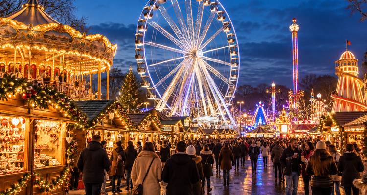 Vibrant Christmas market at night with illuminated Ferris wheel, carousel and crowd of visitors.