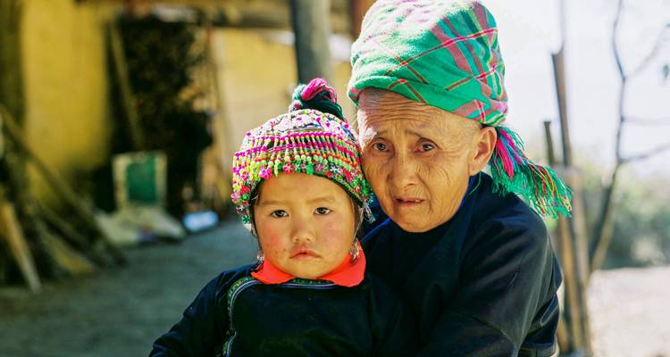 Porträt einer älteren Frau, die ein kleines Kind umarmt, beide in traditioneller Bergstamm-Kleidung.