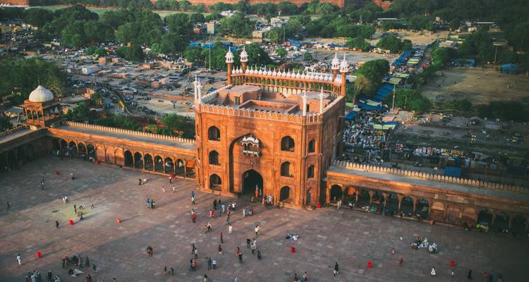 Vue aérienne de la cour de la Jama Masjid à Delhi avec des personnes dispersées à travers la vaste place.